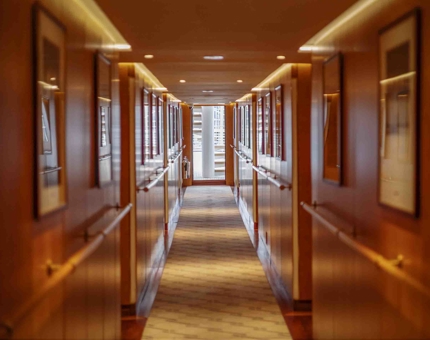 A corridor aboard Fingal Hotel in the Port of Leith. There are framed pictures of Lighthouses lining the walls. 