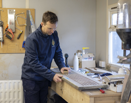 A Maintenance team member sanding scuttle boards from The Royal Yacht Britannia. 