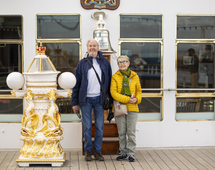 A man and a woman posing for a photo by Britannia's Bell. 