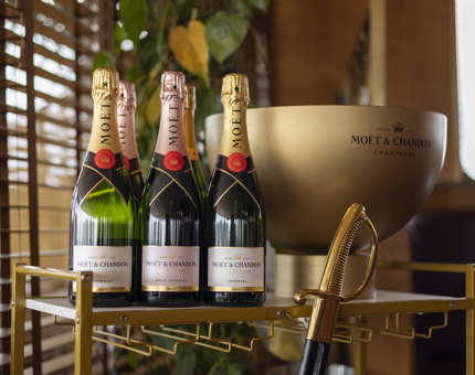 A trolley with bottles of Moet Champagne and a gold ice bucket. 