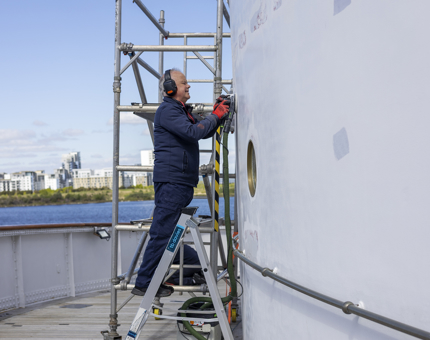 A Maintenance team member sanding down a plastered area of wall ready for painting. 