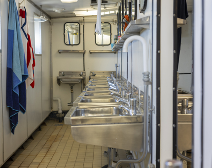 The Junior Rates shower area on the tour route, the wall is lined with a row of silver sinks. 