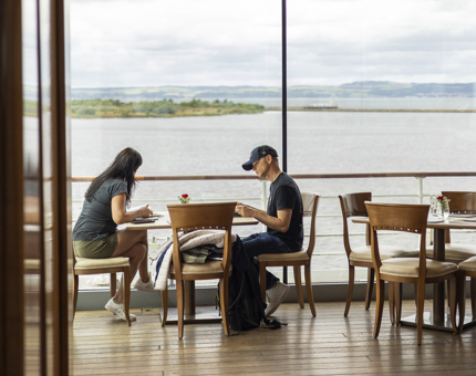 Two guests sitting at a window in the Tearoom overlooking the water in the Port of Leith. 
