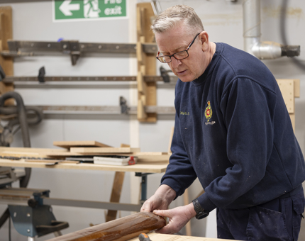 A maintenance team member attaching brass ends to handrails. 