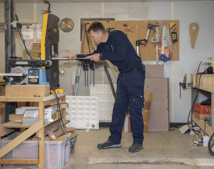 A Maintenance man cutting wood to use for repairs to the Fast Motor Launch boat. 