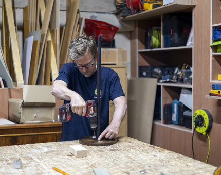 A Maintenance team member holding a drill to assemble small drinks tables for Fingal Hotel. 