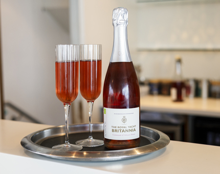 Two glasses and a bottle of pink sparkling wine on a silver tray. 