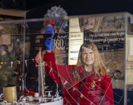 A Housekeeper is polishing a glass case in the Visitor Centre in Leith. 
