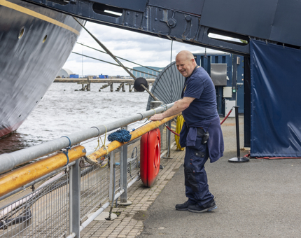 A Facilities Officer cleaning the handrails on the Quayside next to Britannia in the Port of Leith. 
