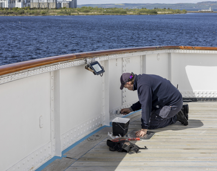 A Maintenance team member adding a coat of white paint aboard Britannia in the Port of Leith. 