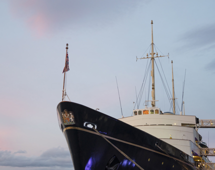 A view of The Royal Yacht Britannia in the Port of Leith from the Quayside at dusk. 