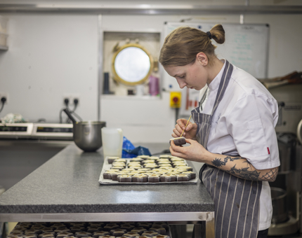 A Chef is in the onboard Galley making star shaped sweets. 