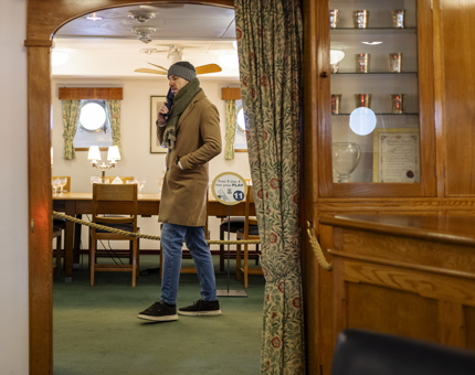 A man listening to an audio guide and walking through the Officers' Wardroom aboard The Royal Yacht Britannia. 