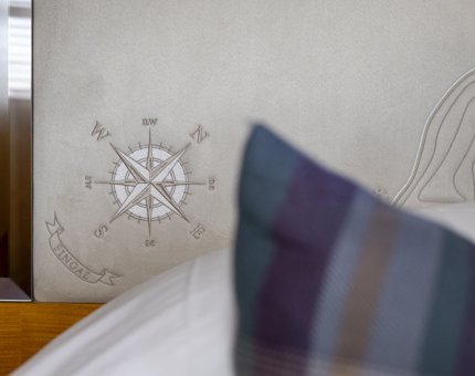 In a cabin aboard Fingal Hotel, a detail of an embroidered compass can be seen on a headboard. 