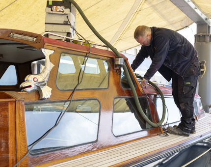 A maintenance man is sanding the Royal Barge on the Quayside. 
