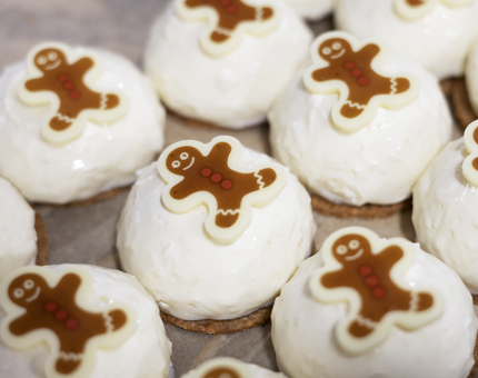 A close up of white sweet treats with a gingerbread man on top of them. 