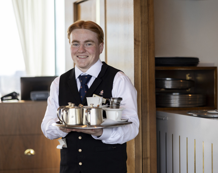 A Hospitality Server, holding a tray of drinks in the Royal Deck Tearoom. 