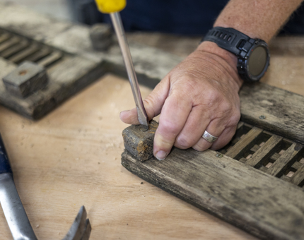 A close up of a hand using a screwdriver on a piece of wood. 