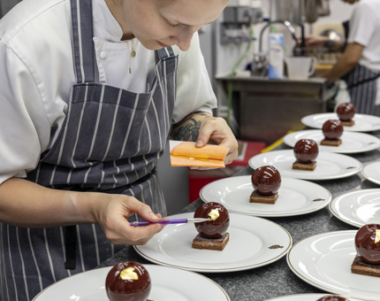 A Chef is adding edible gold leaf to chocolate desserts in the Galley aboard Britannia in Leith. 