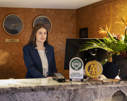 A woman standing behind a reception desk aboard Fingal Hotel. 