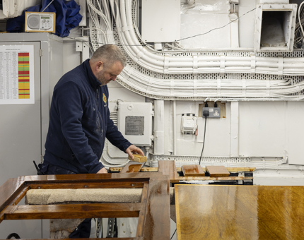 A Maintenance man sanding a door from the Verandah Deck. 