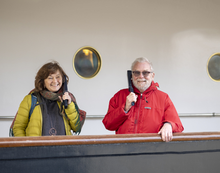Two visitors listening to audio guide handsets on Britannia's deck.