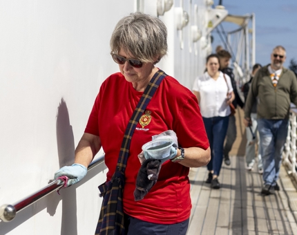 A Housekeeper is polishing handrail on the decks of the Port side of Britannia. 