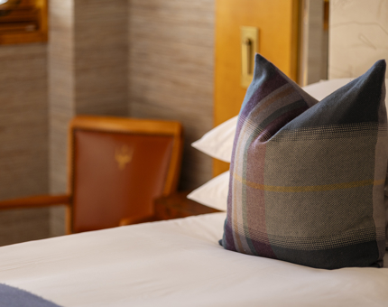 A pillow detail in one of Fingal Hotel's cabins. It is woven tartan in purples, blues and greens. 