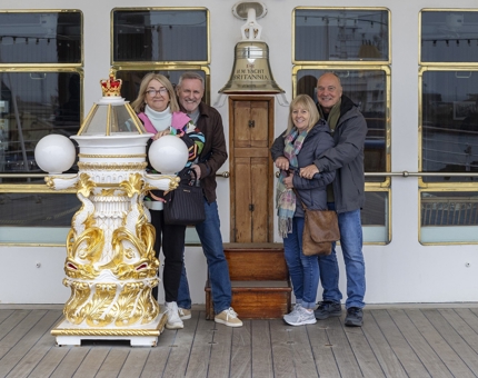  4 Visitors pose by Britannia's Bell on the Verandah Deck. 