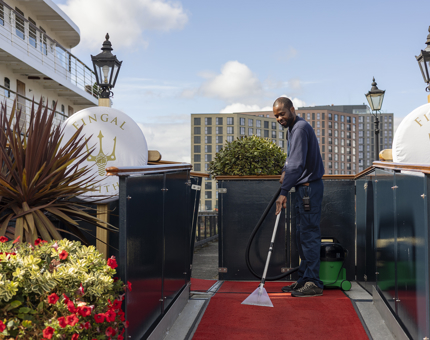 Outside Fingal Hotel in the Port of Leith, a man is cleaning a red carpet. 