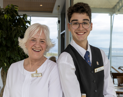 Two Tearoom team members are posing for a photo. It is a woman and a young man. 