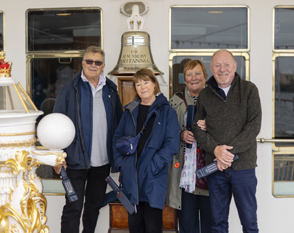 Two men and two women pose for a photo by Britannia's Bell. 