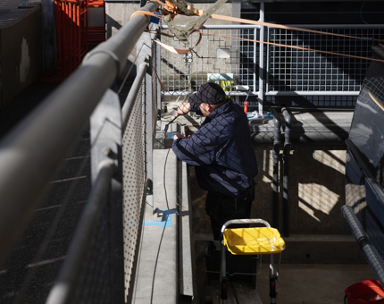 A maintenance man is in the empty pond of the Royal Barge, adding coat of silver paint to the metal work. 