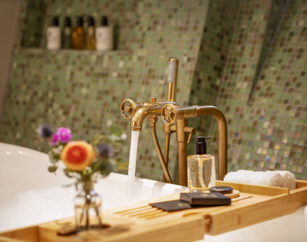 A bath is running inside a cabin at Fingal. There are flowers on the bath tray. 