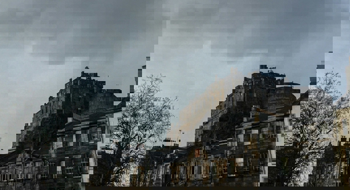 A view of Edinburgh Castle from below. There are terraced buildings in the foreground. 